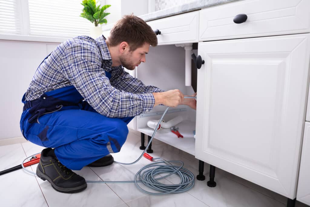 Plumber Cleaning Clogged Sink Pipe